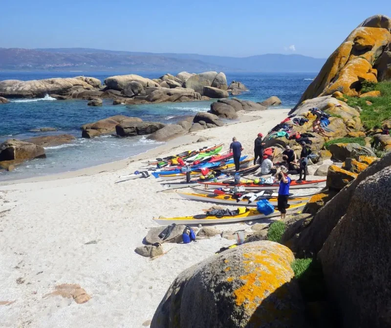 Kayaks alineados en la arena blanca durante una jornada de práctica y descanso.