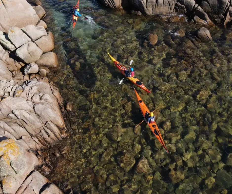 Dos kayaks navegando entre formaciones rocosas en aguas cristalinas.