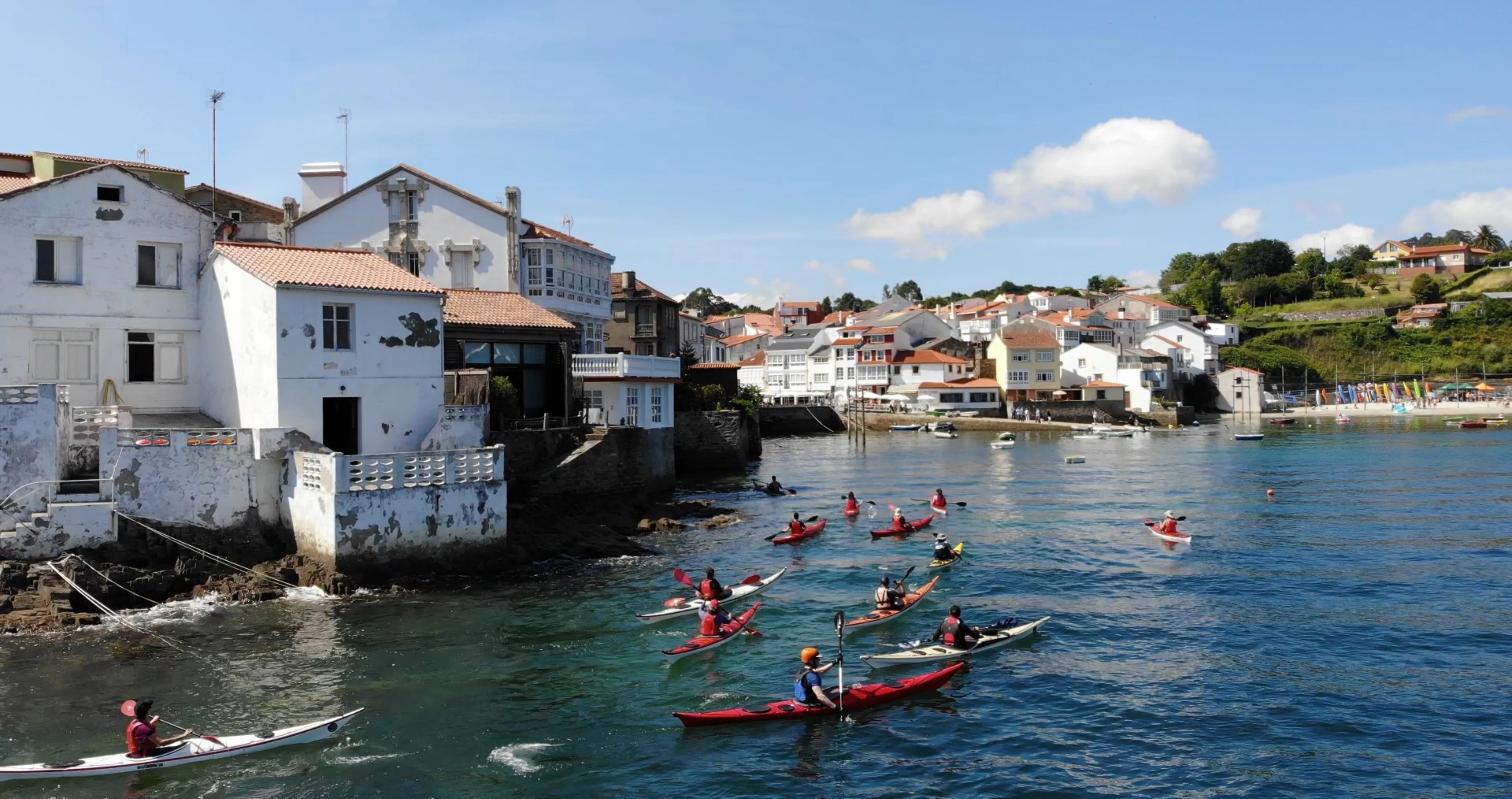 Grupo de palistas saliendo en kayak de mar desde la base del club en el puerto de Redes, Ares