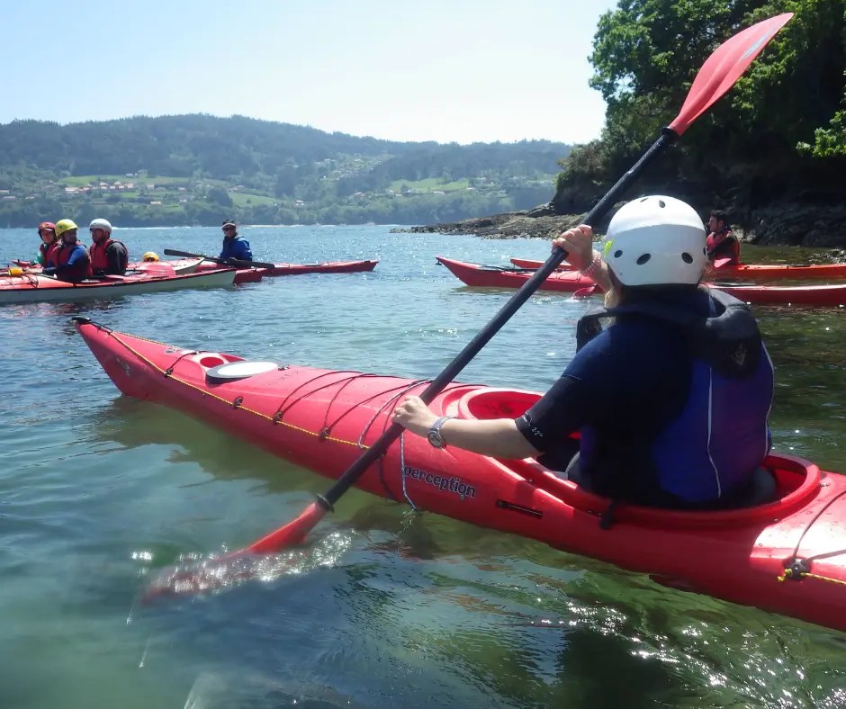 Instructor enseñando técnicas de paleo en un kayak rojo de travesía