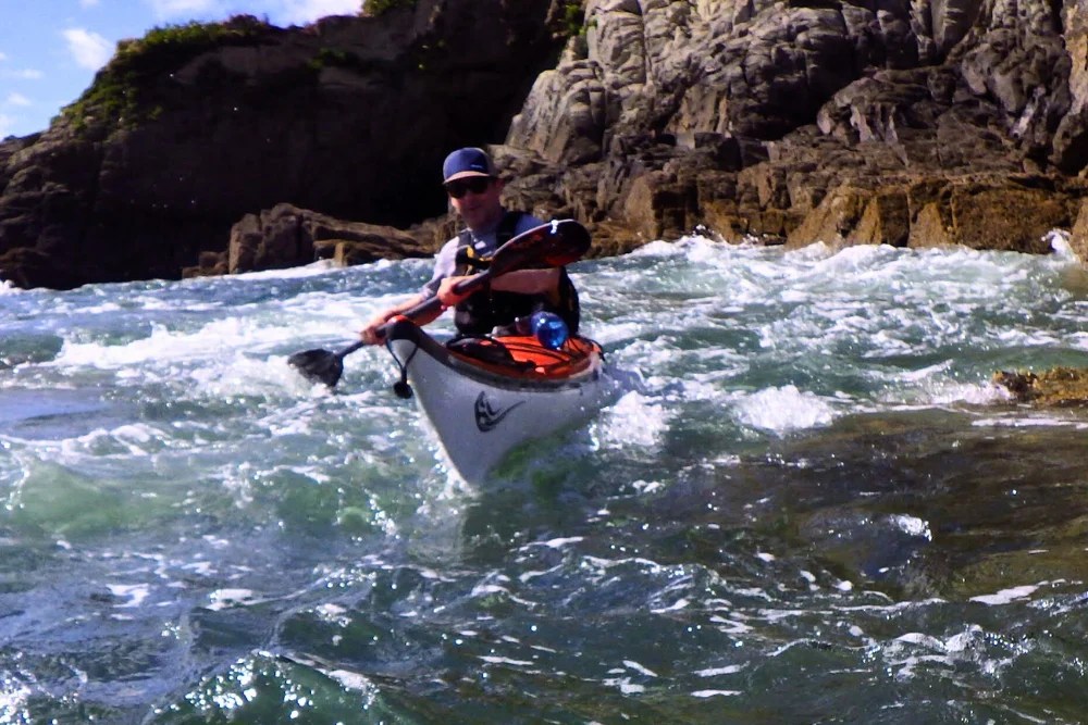Palista realizando maniobras de kayak de mar en condiciones de oleaje moderado para certificación ACA Nivel 3