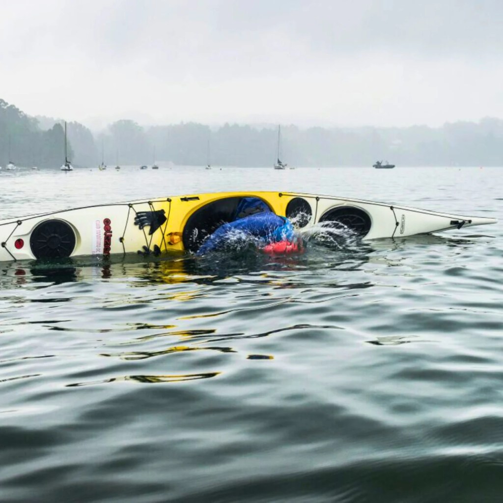 Palista realizando la maniobra de esquimotaje o Eskimo Roll con un kayak de mar en aguas de Redes. Galicia